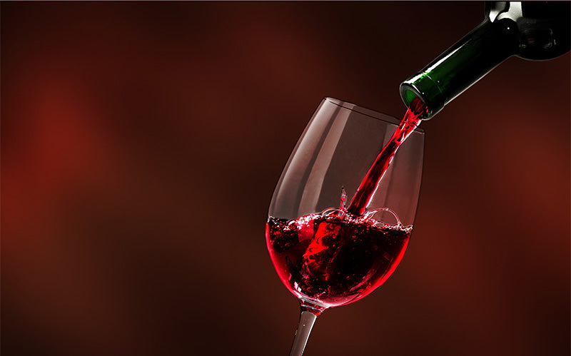 Red wine being poured into a crystal glass against a dark background